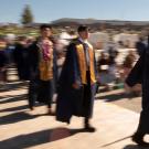 A line of students in graduation regalia enters UC Davis Health Stadium.