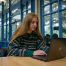 A student works on her laptop in a coffee shop at UC Davis. 