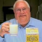 John Bruhn holds glass of milk amid old UC Davis dairy packaging