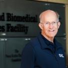Ken Burtis, unmasked, outside, in front of sign on building: "Genome and Biomedical Science Facility"