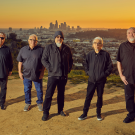 Band of men dressed in black with urban scenery behind them