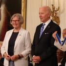 Sister Simone Campbell (in white blazer) and military aide (holding medal) flank President Joe Biden