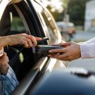 Hands of people doing a phone purchasing transaction from a car