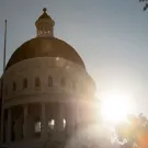 A lens flare is created by the sun shining out from behind the dome of the California State Capitol.