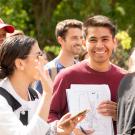 A student smiles outside with his papers at UC Davis. 