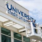Worker installs University Credit Union Center signage.