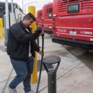 Person handles charging cable in bus yard with red buses
