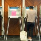 Two women, backs to camera, in voting booths