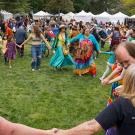 People hold hands and dance on large grassy field