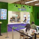 Green-accented acai café interior with service counter, digital menus and seated customers