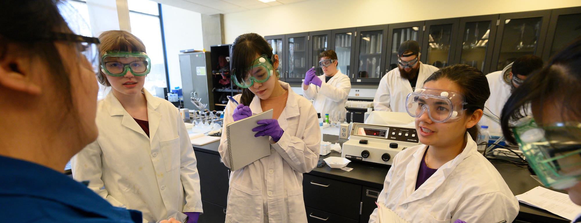 Students in goggles confer in a lab at UC Davis. 