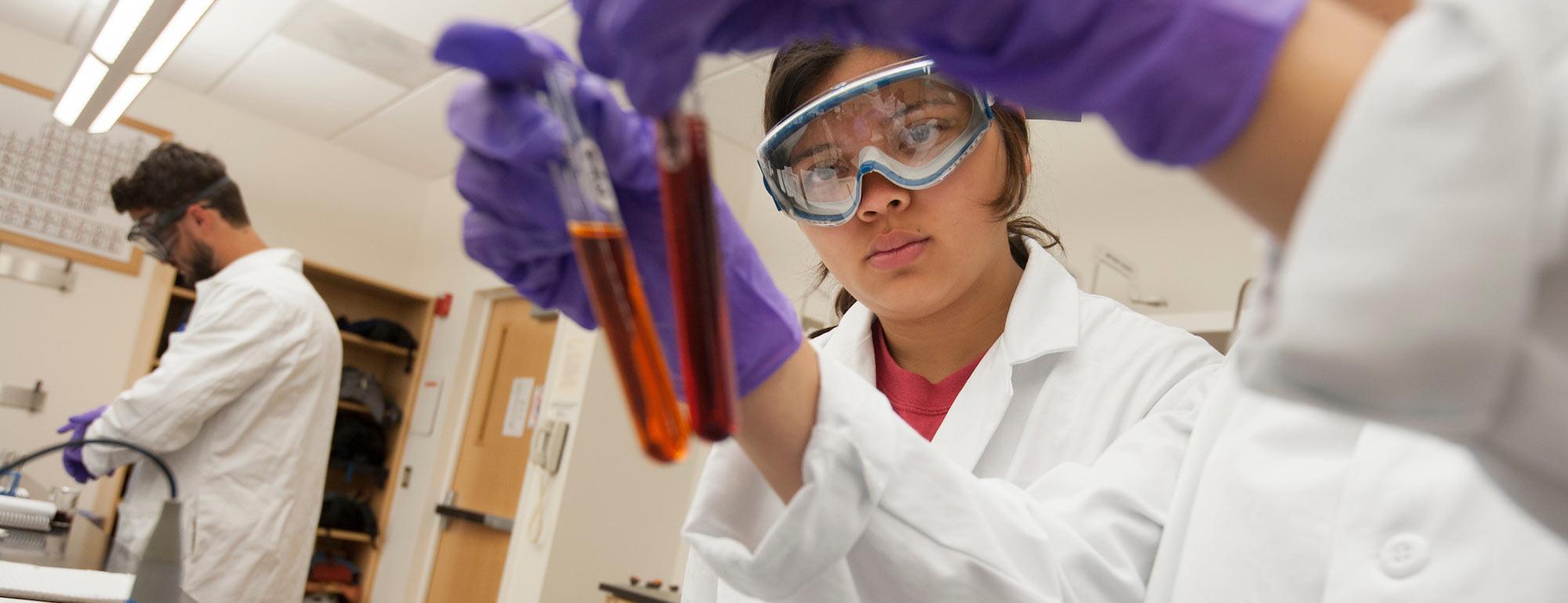 Two female students evaluate the color of a chemical sample