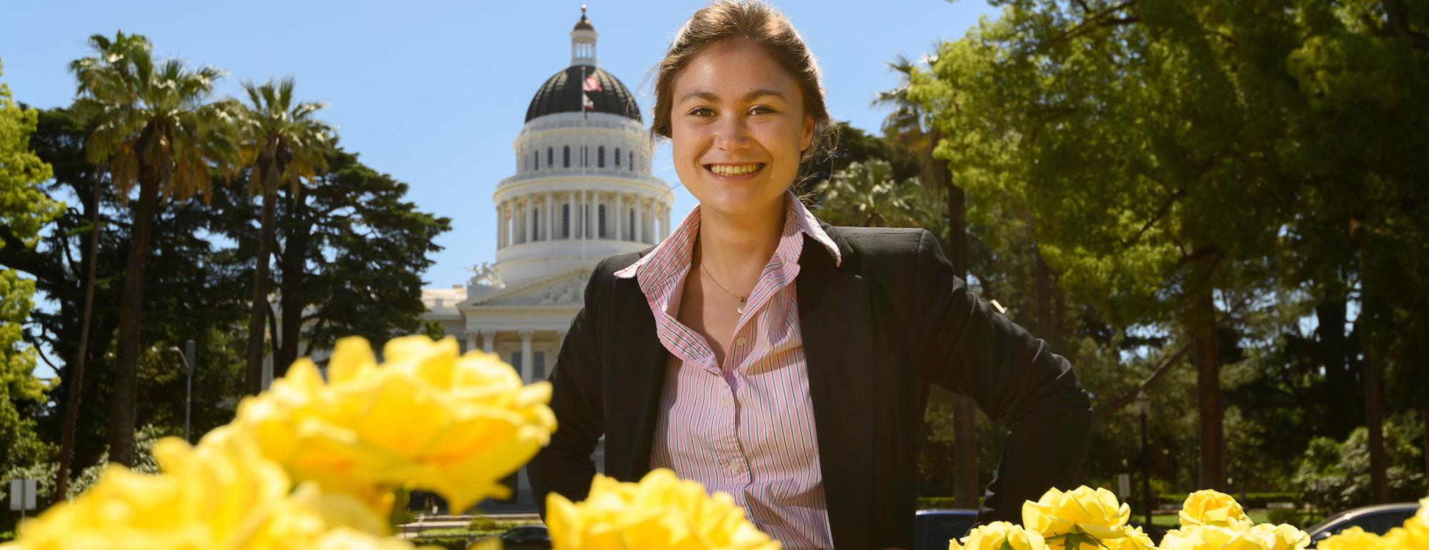 A female student poses in front of the state capitol building