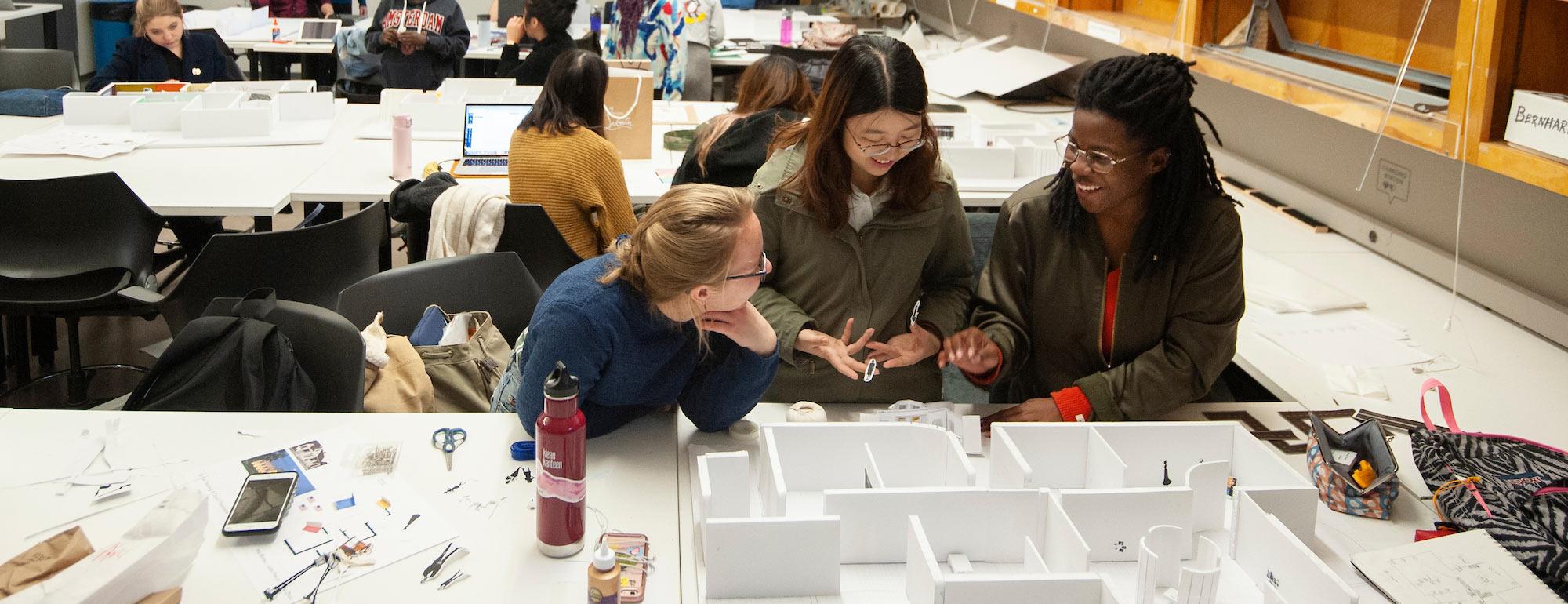 Three female students discussing a design model