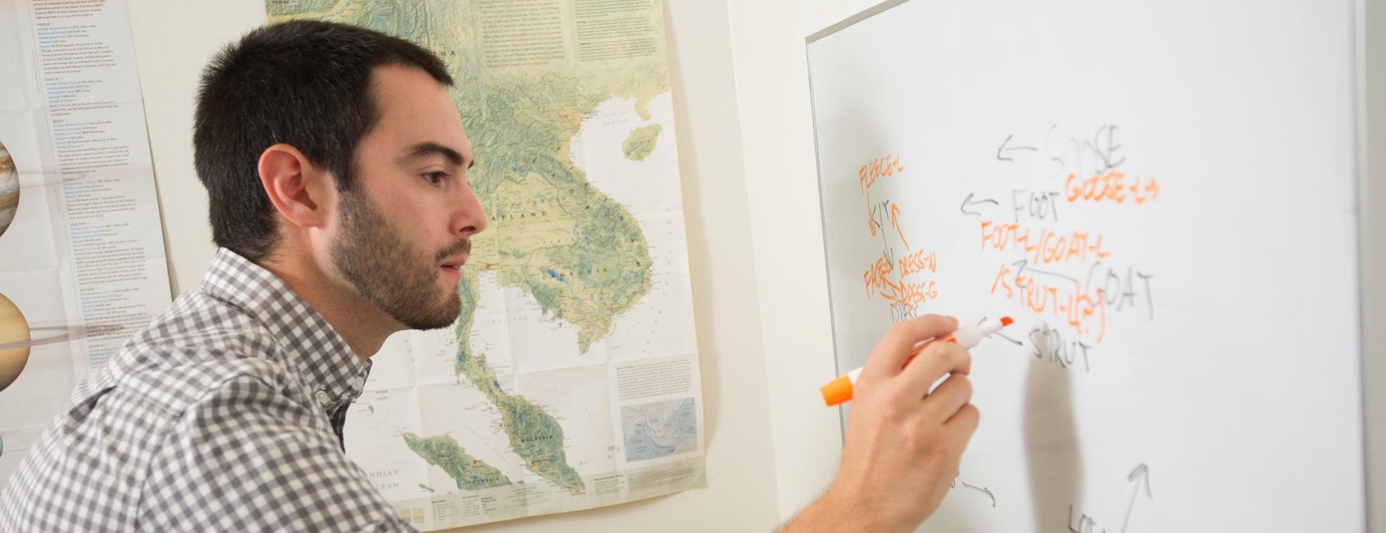 A PHD candidate evaluates word structure on a whiteboard