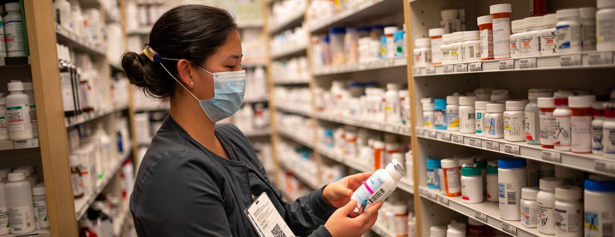 A woman examines a shelf of prescription medicine