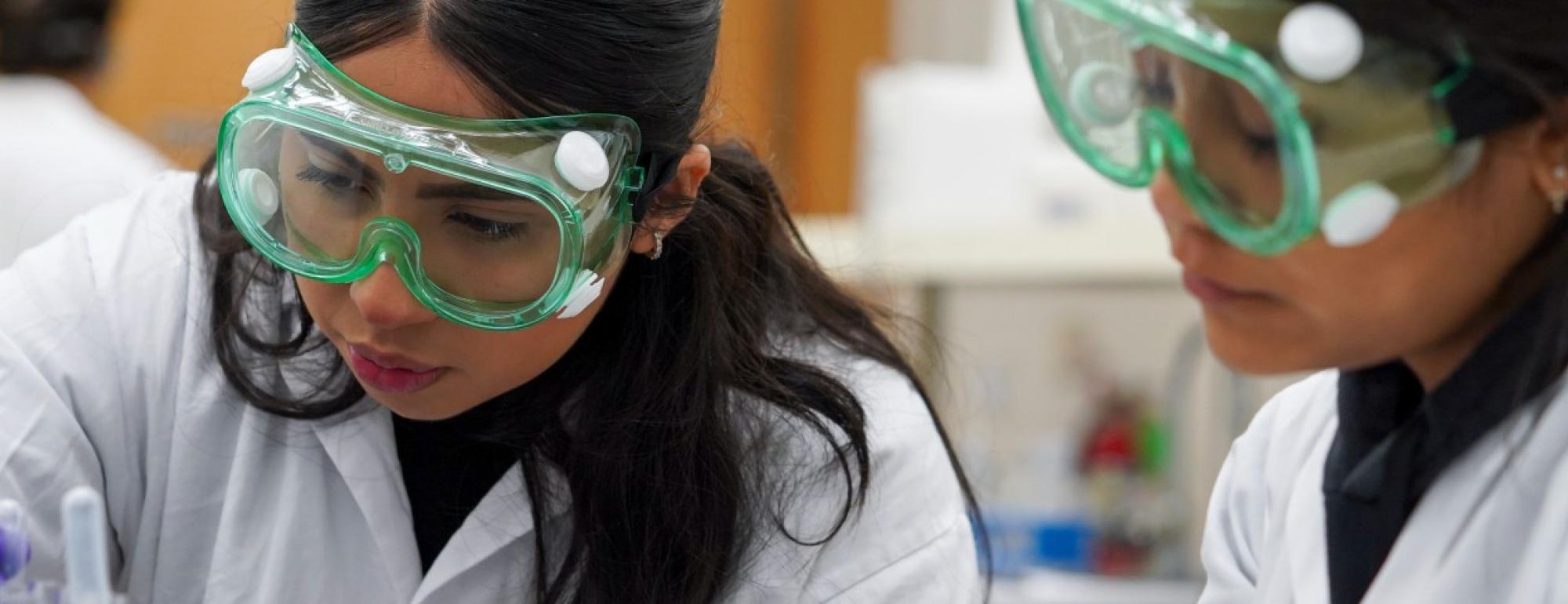 two chemistry tudent wear goggles at a lab bench while dealing with pharmaceuticals at UC Davis