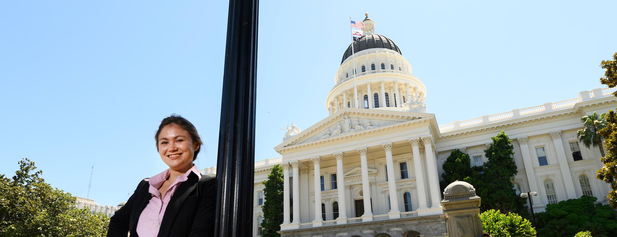 A female student poses with the California State Capitol building in the background