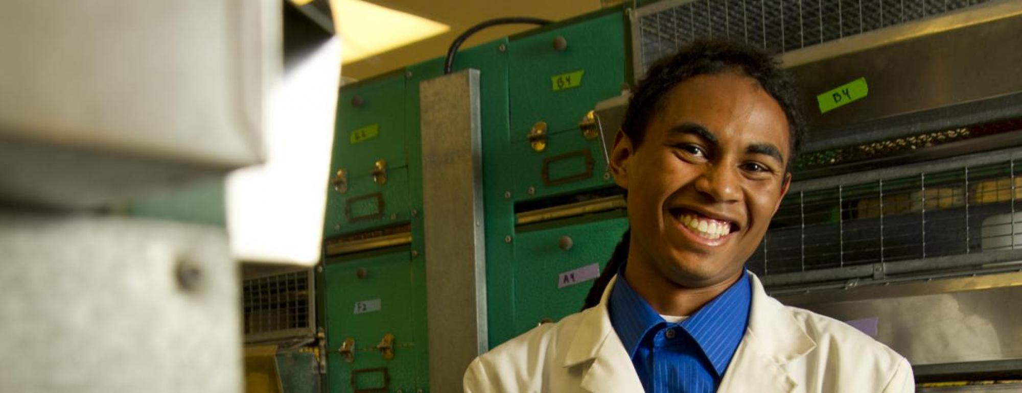 student wearing lab coat smiles in lab