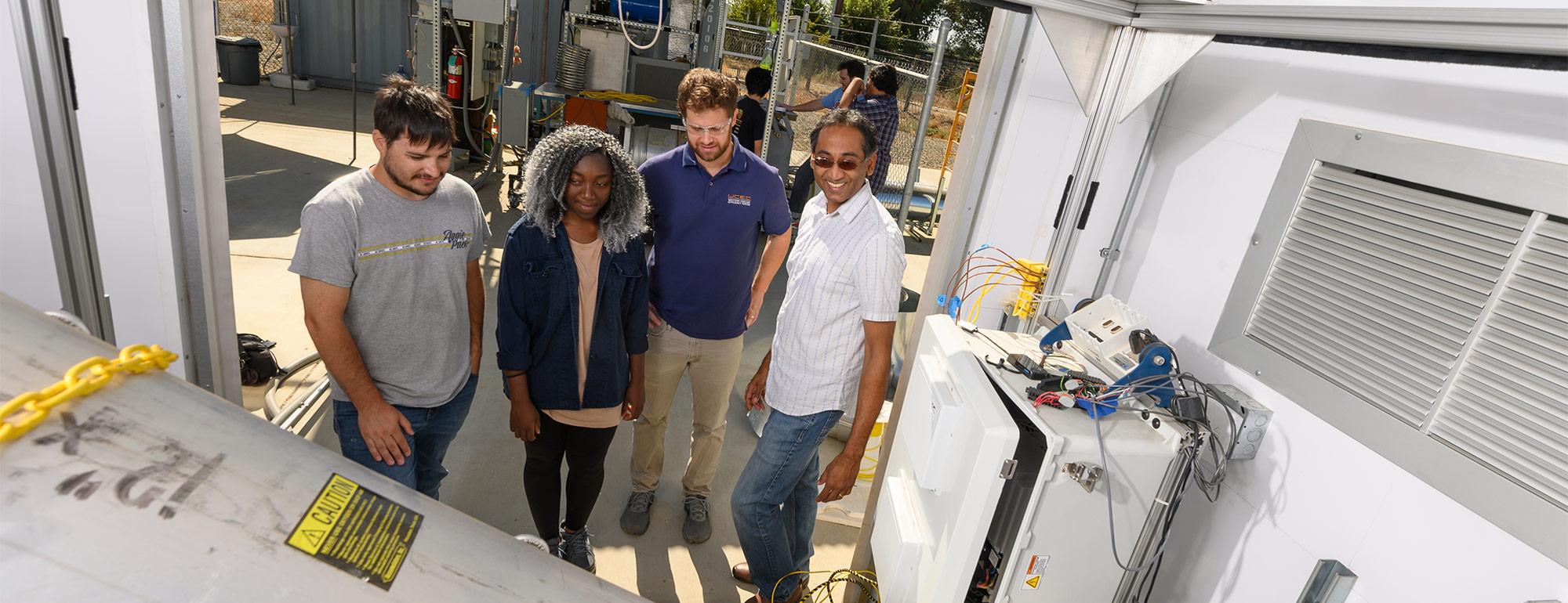 3 students working with Professor Vinod Narayanan at the Western Cooling Efficiency Center about a project.