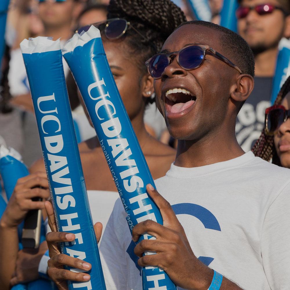A male student cheers on the Aggies at a football game