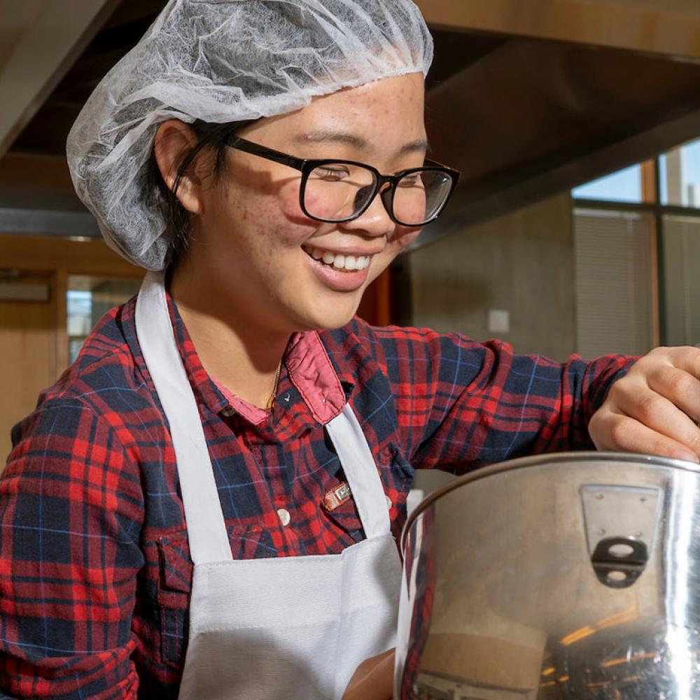 A female student mixes a food preparation in the UC Davis food lab