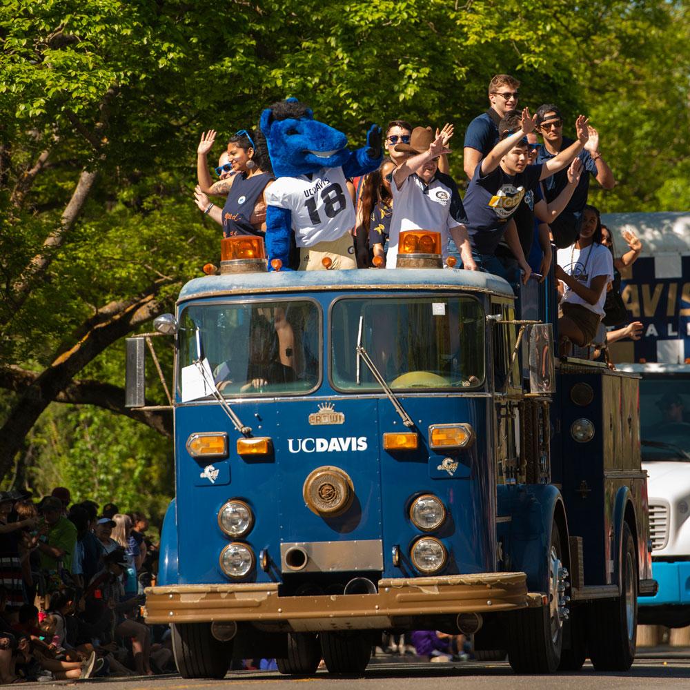 students aboard a truck waving to the crowd during a Picnic Day parade