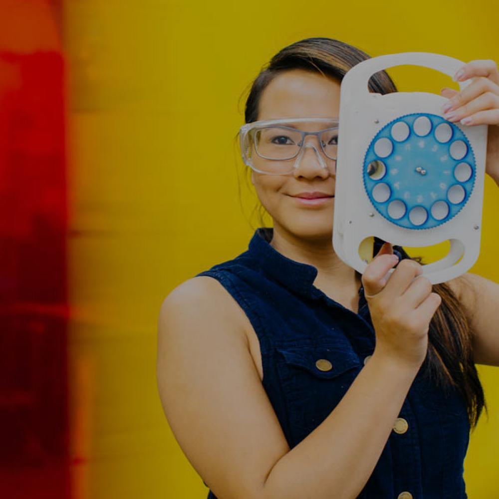 A student holds up portable eye examination technology that she invented