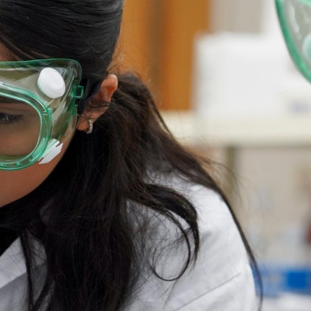 two chemistry tudent wear goggles at a lab bench while dealing with pharmaceuticals at UC Davis