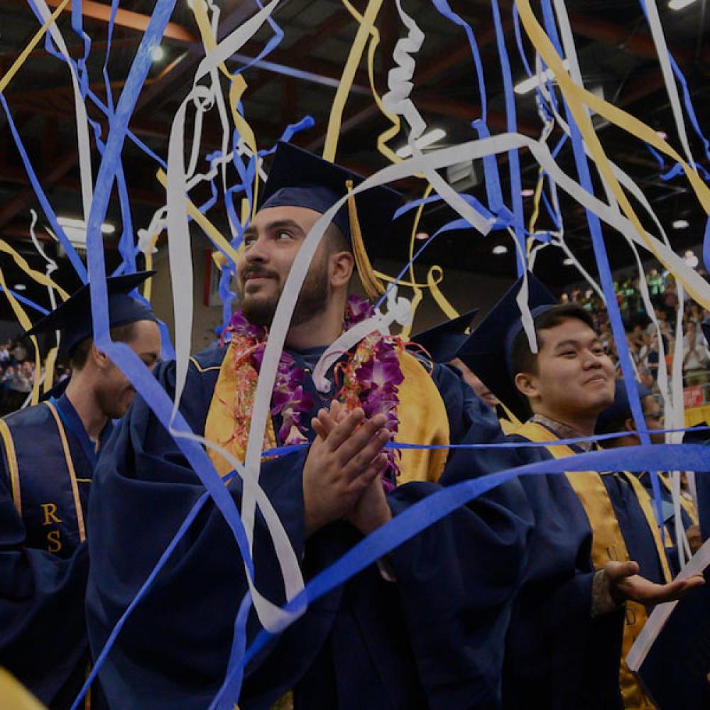 A student enjoys commencement as streamers fall from the ceiling