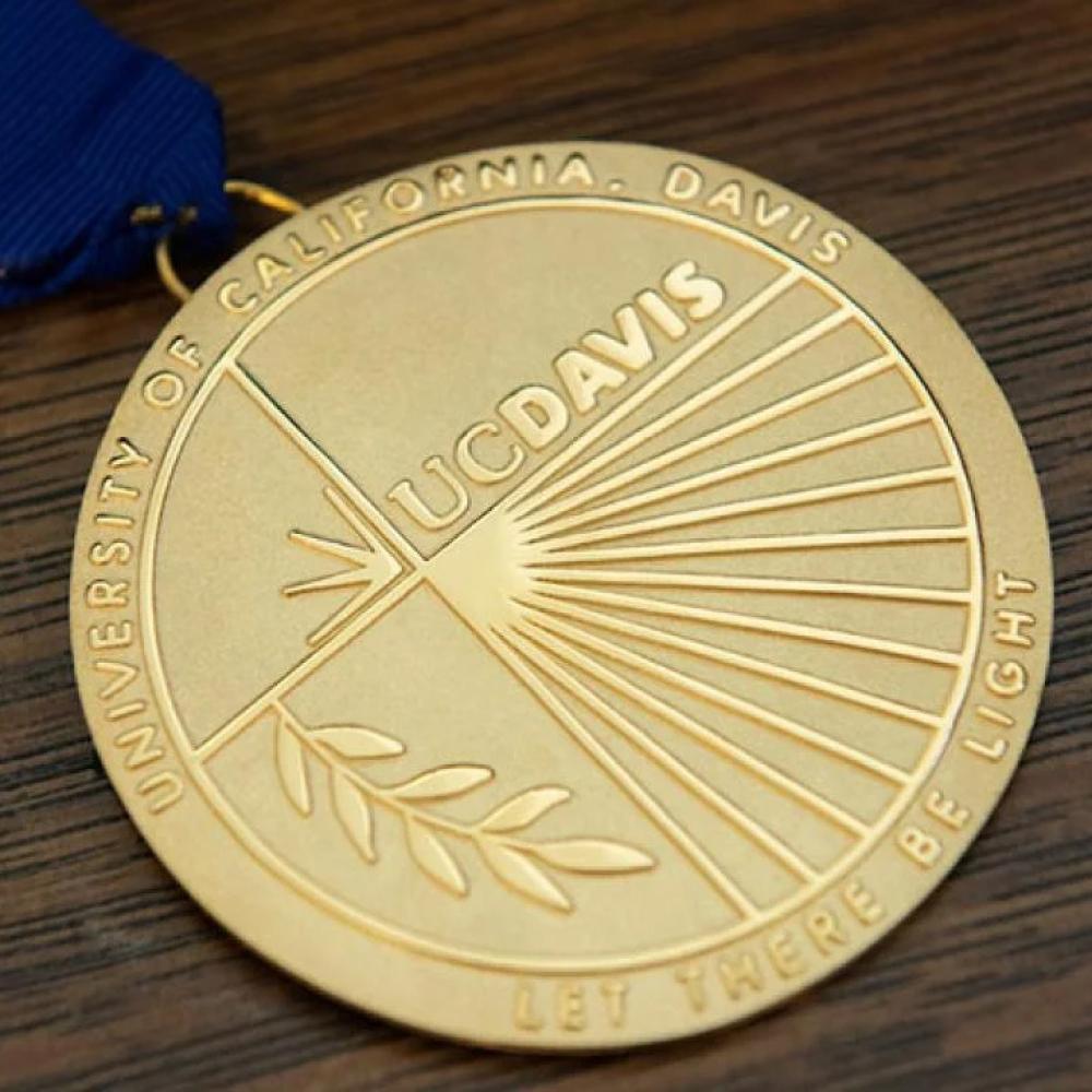 a gold UC Davis commencement award medal on a blue ribbon