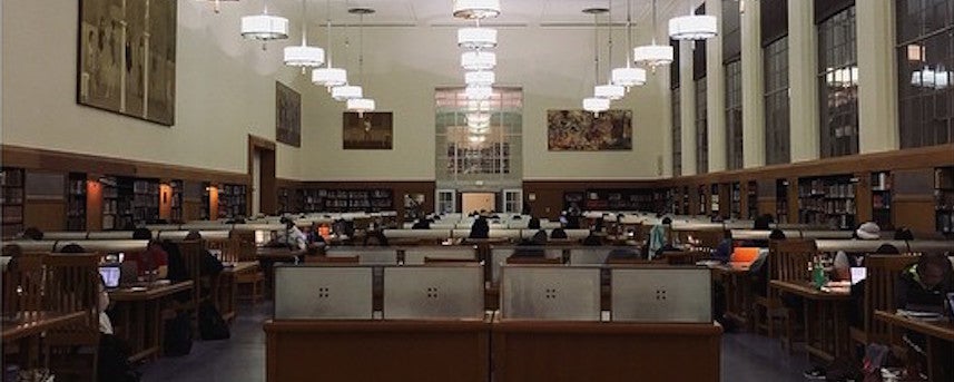 Rows of desks and students studying inside the library reading room