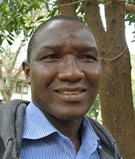 African man in gray sweatshirt over a light blue shirt.