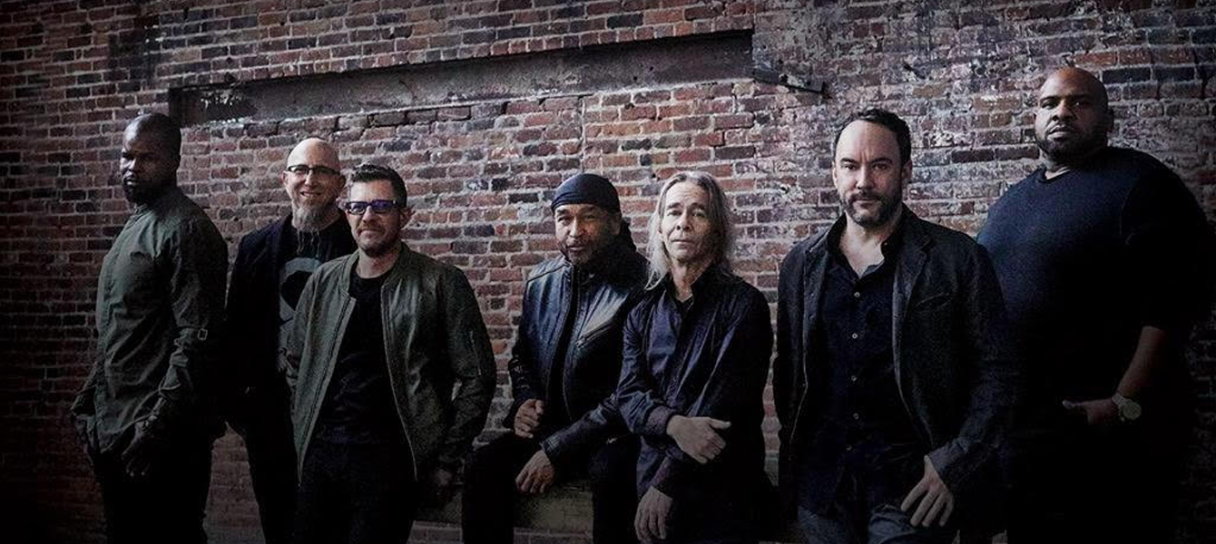 Members of the Dave Matthews Band standing in front of a brick wall.