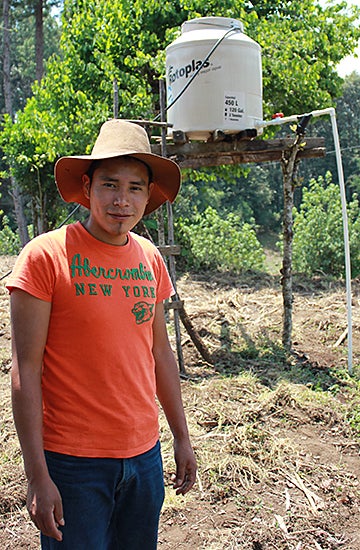 Young man in straw hat, T-shirt and jeans stands in front of water tower