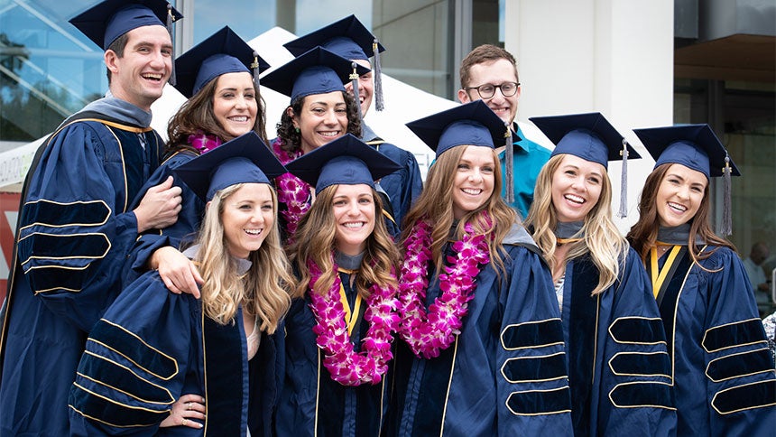 Ten happy graduates pose for a photograph