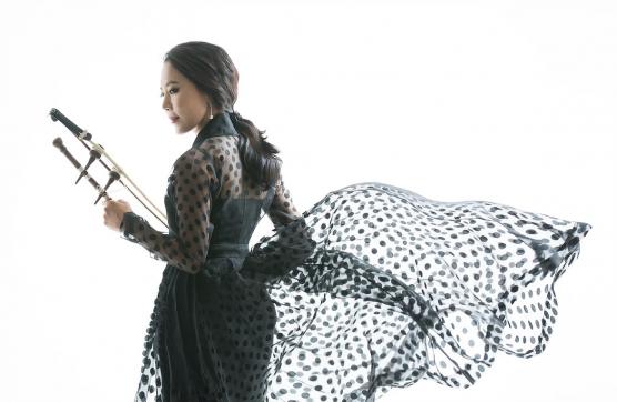 Soo-Yeon Lyuh holding her haegeum, her polka-dot skirt blowing in the wind.