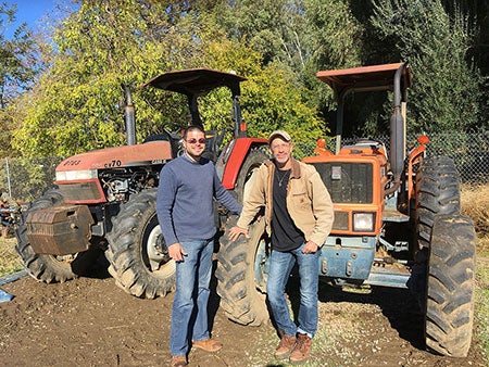 Two men in front of tractors